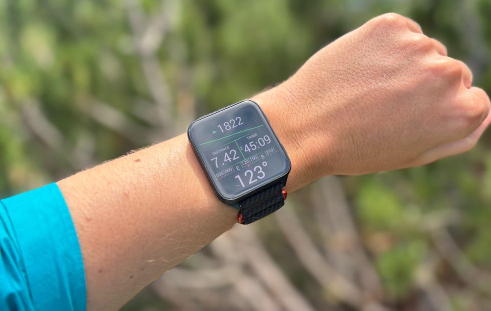 A person who wears a colorful square smartwatch while hiking
