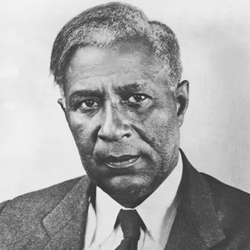 black and white image of garrett morgan, he wears a suit jacket, collared shirt, and tie and looks directly at camera