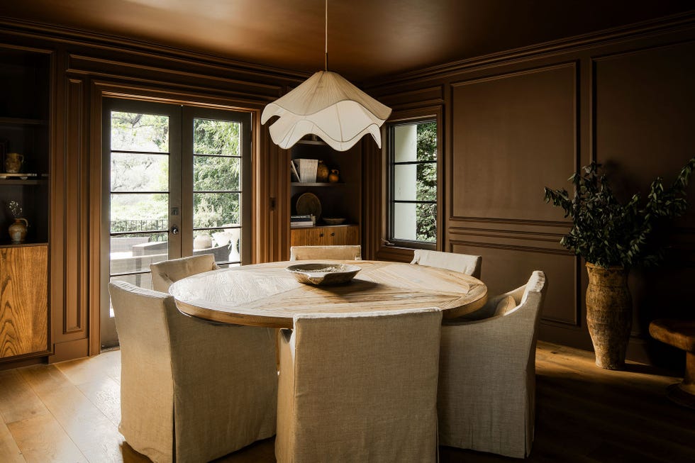 Dining area featuring a round wooden table and upholstered chairs and dark brown walls dining area featuring a round wooden table and upholstered chairs and dark brown walls