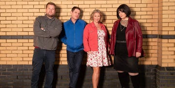 group of four individuals posing against a brick wall