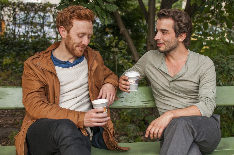 gay couple drinking coffee in the park