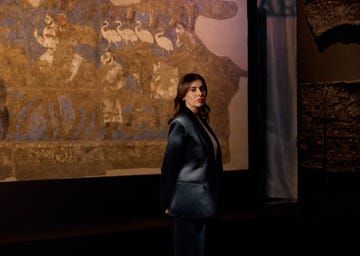 a figure stands in front of a historical mural backdrop