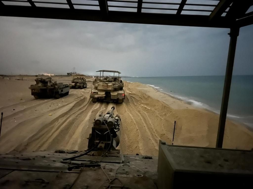 military vehicles driving on a sandy beach