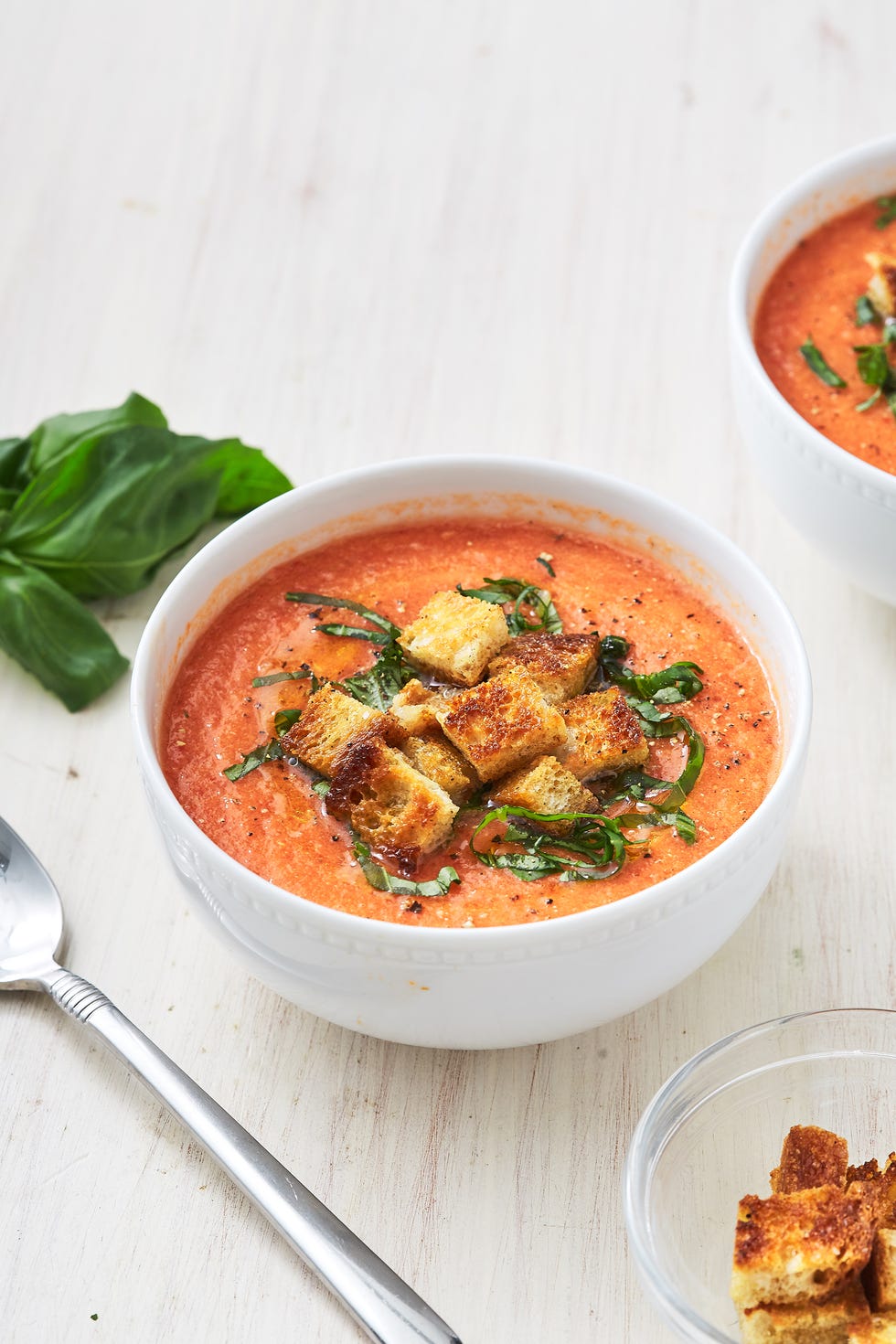 bowl of gazpacho garnished with basil and croutons