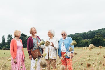group of four older women laughing in a wheat field