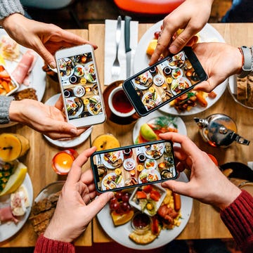 Friends taking pictures of food on the table with smartphones during brunch in restaurant Así comen los millennials