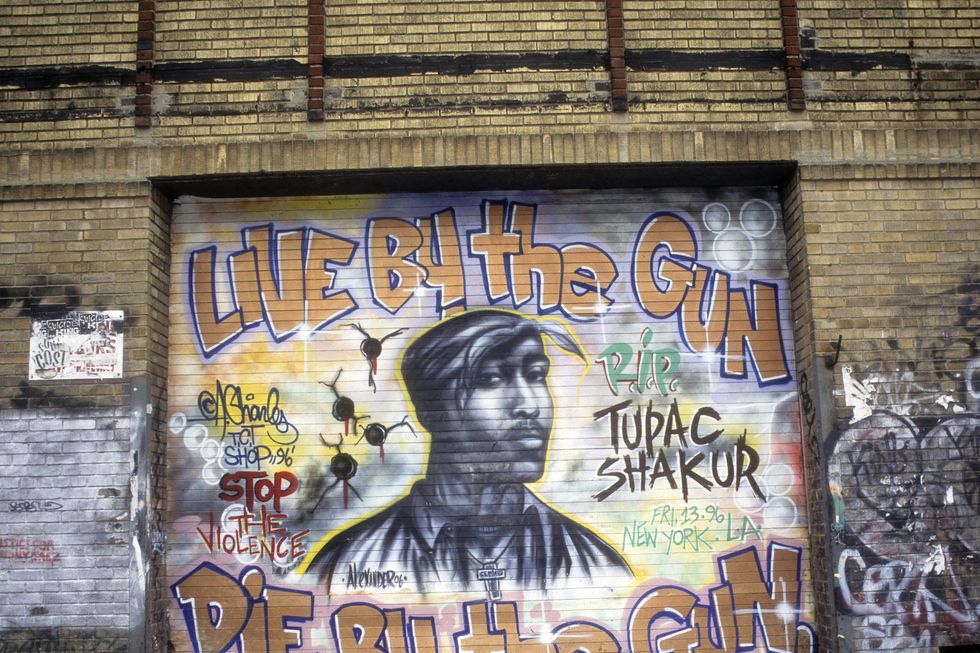 a mural of tupac shakur on a brick wall, with the words live by the gun die by the gun around it, along with stop the violence, and rip tupac shakur
