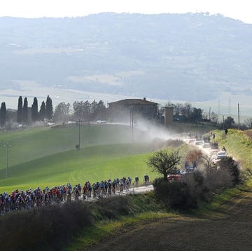 peloton op een strook strade bianche in toscaans landschap