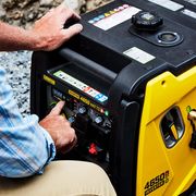 person pressing buttons on a yellow generator