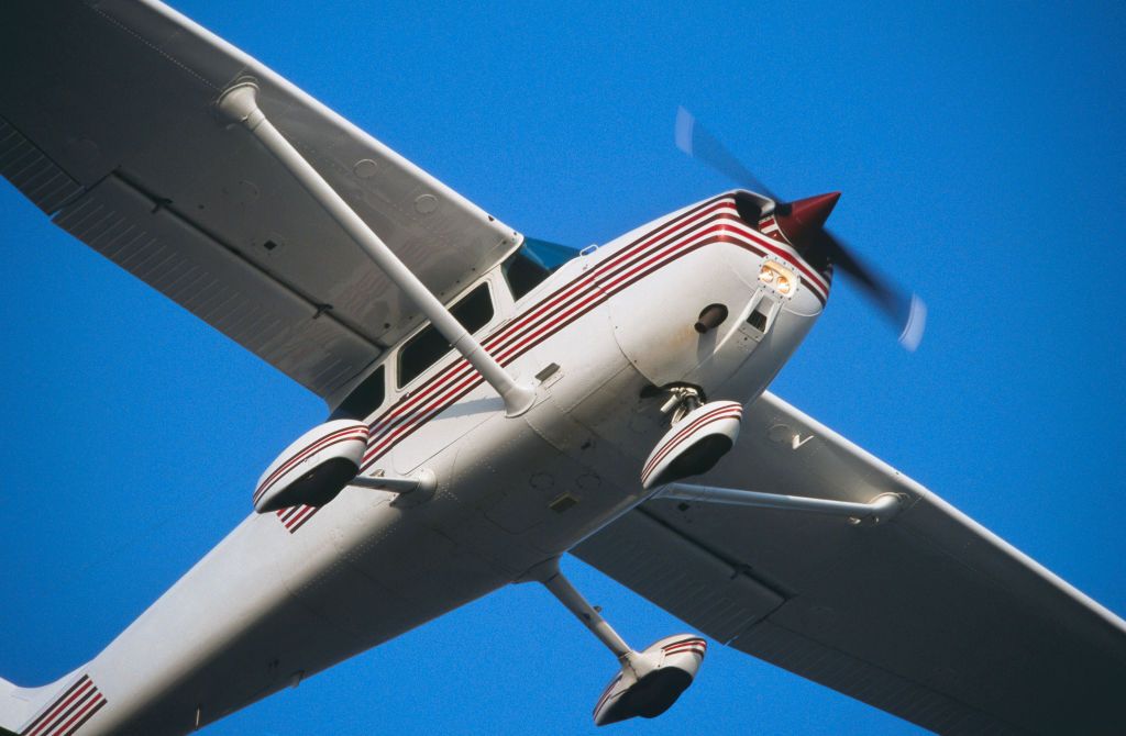 generic Cessna 172N Skyhawk climbing out after take-off with undercarriage wheel spats and landing-lights on