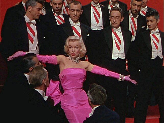 a person in a dress dancing with a group of people in suits
