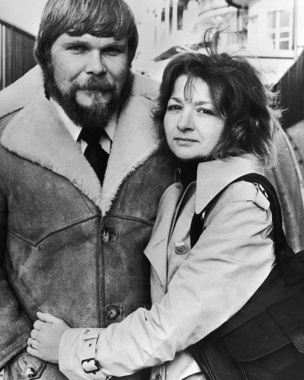 a man and a woman hug and look at the camera
