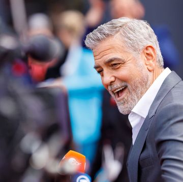 george clooney smiles and looks to the left, he wears a gray suit jacket and white collared shirt