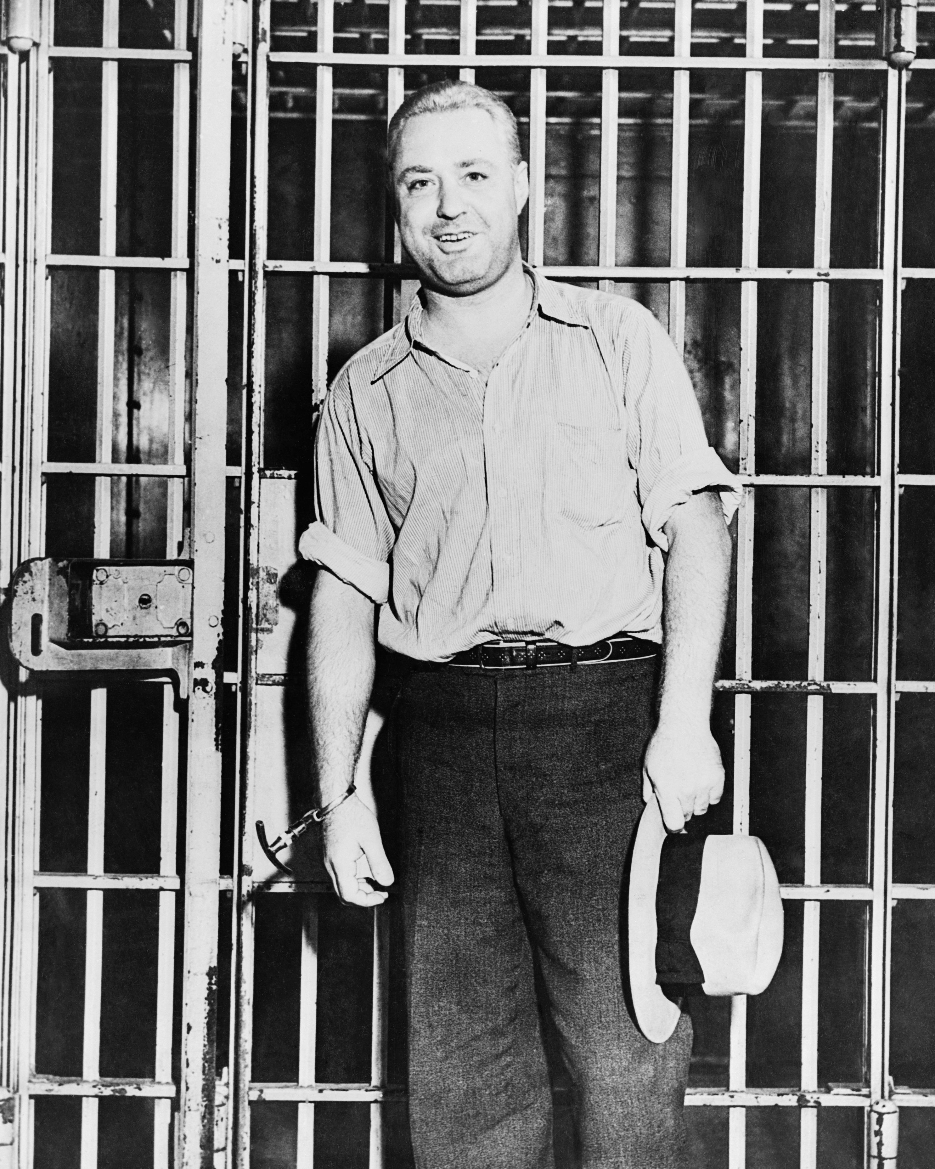 man handcuffed and standing near a prison cell