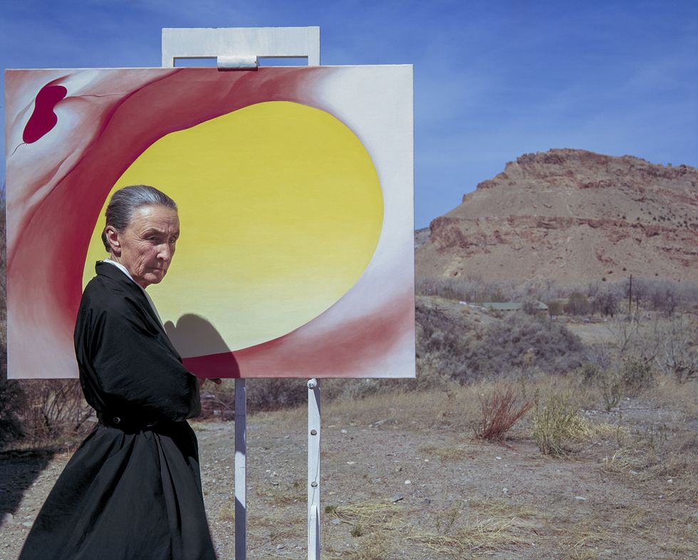 Georgia O'Keeffe poses outdoors beside an easel with a canvas from her series, 'Pelvis Series Red With Yellow,' in Albuquerque, New Mexico, 1960