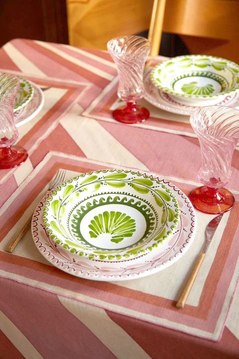 a pink striped tablecloth with green and pink patterned plates and glassware