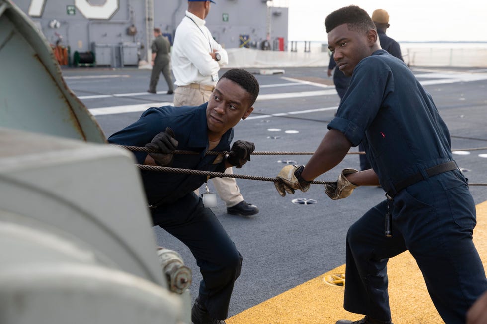 newport news, va oct 19, 2019 aviation boatswain's mate equipment airman isaiah gamble, left, from charlotte, north carolina, and aviation boatswain's mate equipment airman achigbue uche, from columbus, ohio, both assigned to uss gerald r ford's cvn 78 air department, reel a messenger cable while installing an arresting cable on the flight deck ford's air department installed the ship's arresting gear cables for the first time since undergoing their post shakedown availability us navy photo by mass communication specialist 2nd class brigitte johnston this image has been altered by blurring out badges for security purposes