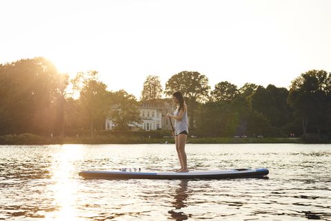 germany, hamburg, young woman on paddleboard enjoying summer