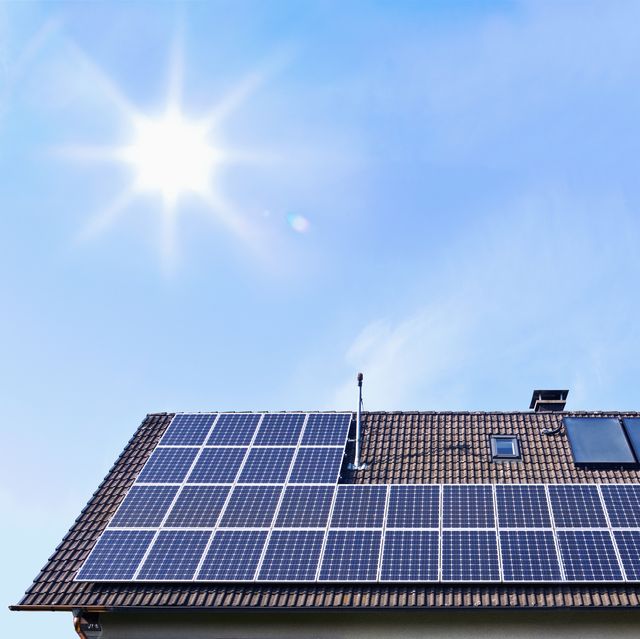 germany, solar panels on houseroof in front of blue sky with sun