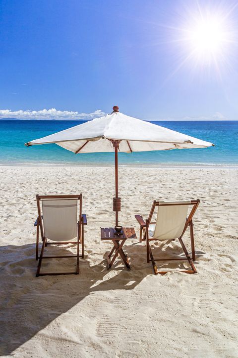 two deckchairs and a sunshade on the beach facing the sun