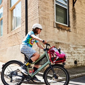 young boy on a bike riding around a corner of a brick building
