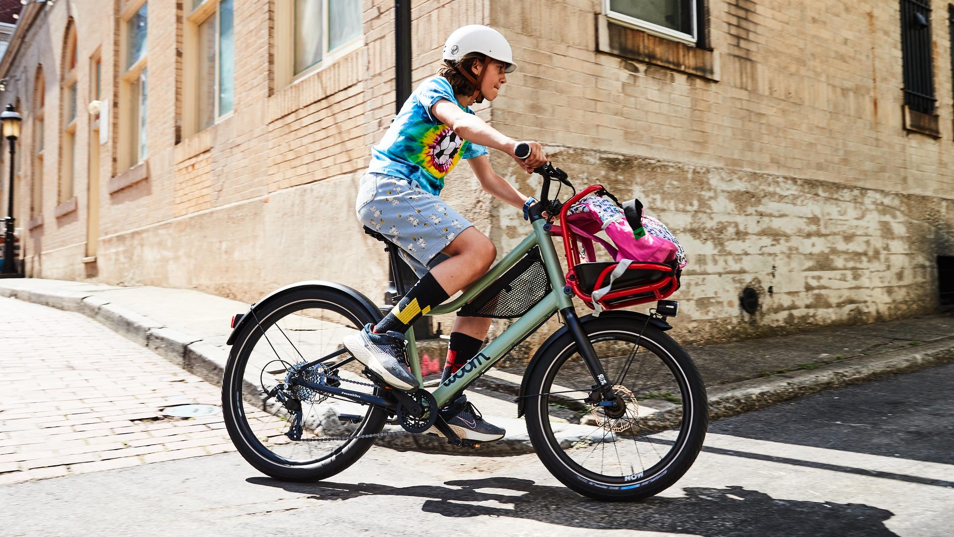 young boy on a bike riding around a corner of a brick building