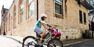 young boy on a bike riding around a corner of a brick building