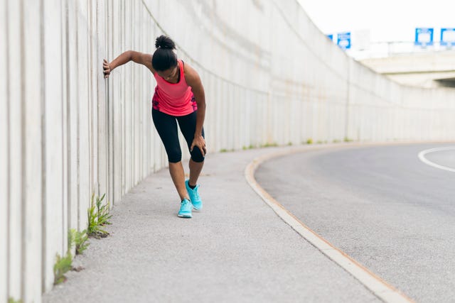 young woman taking a break from running, having a knee injury