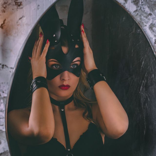 close up portrait of a young adult girl dressing a leather rabbit mask in front of mirror