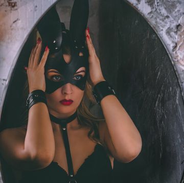 close up portrait of a young adult girl dressing a leather rabbit mask in front of mirror
