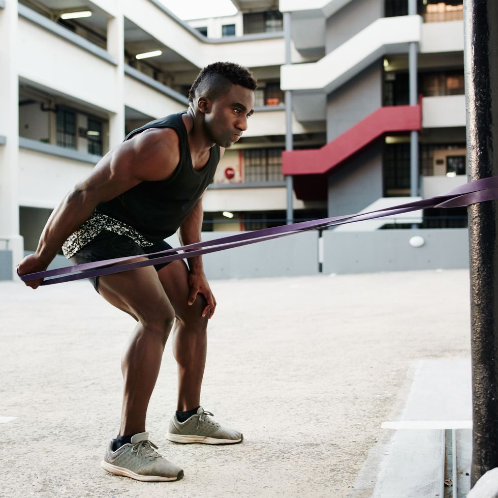 shot of a handsome and sporty young man working out with resistance bands in the city