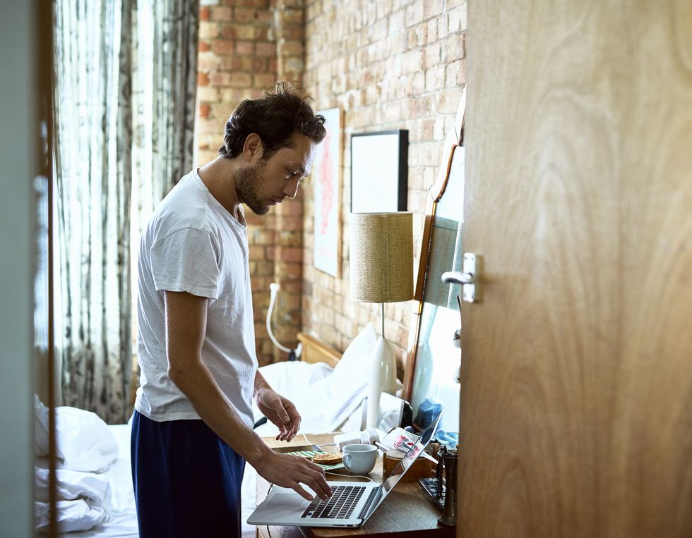 Mature businessman in hotel room getting ready and using laptop