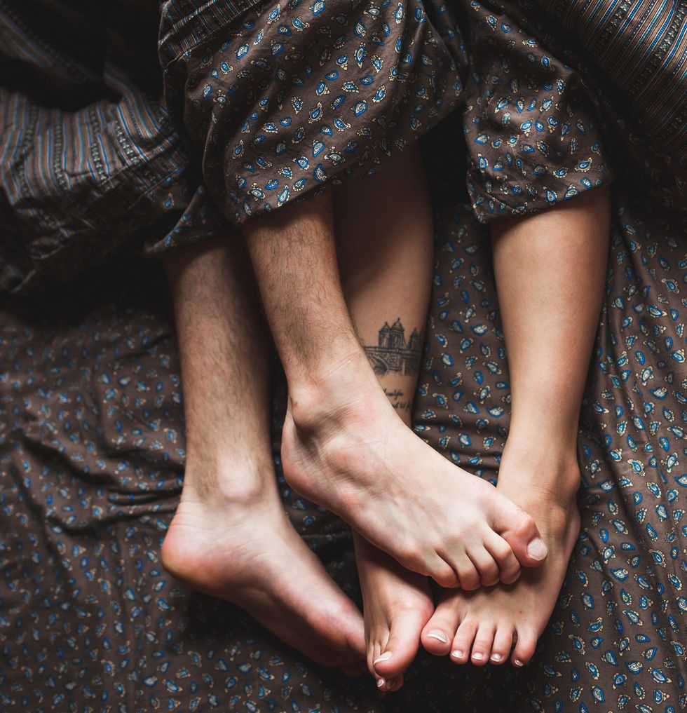Legs of young couple lying in bed together in morning, romantic mood