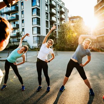 an urban fitness group for women warming up before a run through the city together