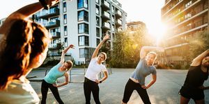 an urban fitness group for women warming up before a run through the city together