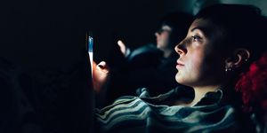 Women in bed in darkness using mobile phones