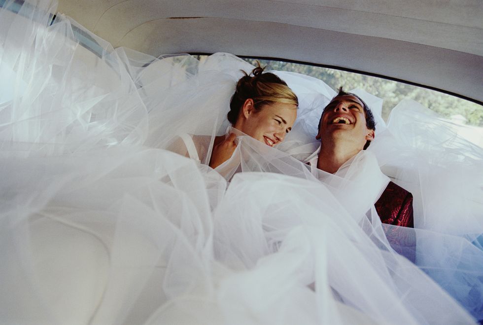 Newly weds laughing in back of car