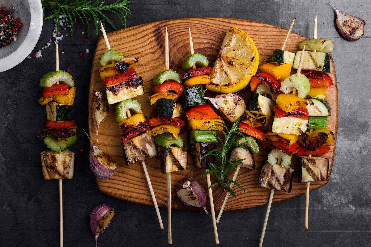 colorful grilled summer seasonal vegetables skewers on rustic wooden board viewed from above