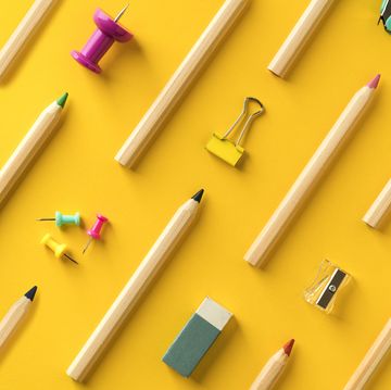 School supplies and coloring pencils flat lay on yellow background