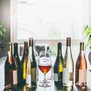 Variety of wine bottles and glasses on table in modern living room