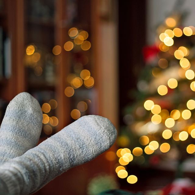 Close-up of relaxing feet at home with bokeh of christmas lights behind