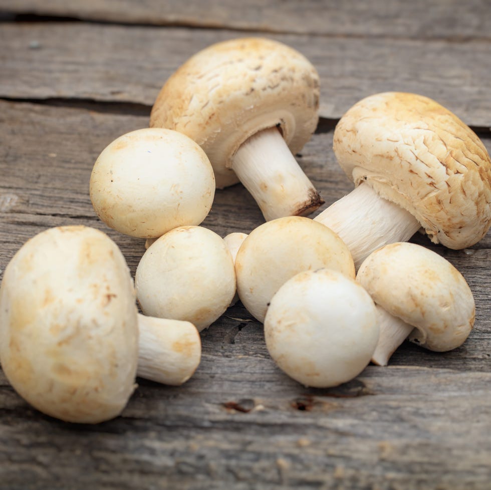 Stack of white button mushrooms, on wooden surface stack of white button mushrooms, on wooden surface