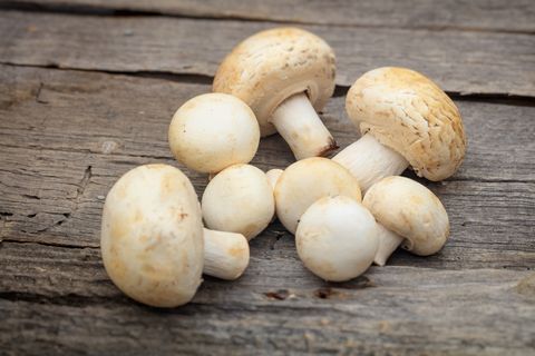 stack of white button mushrooms, on wooden surface