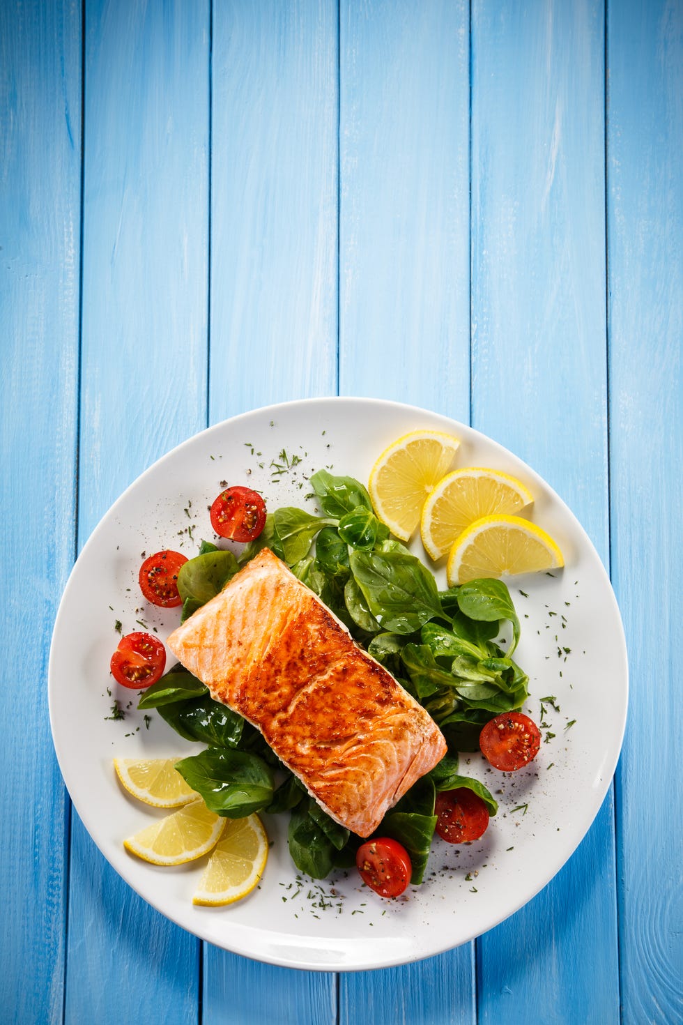 Grilled salmon with French fries and vegetables on wooden table