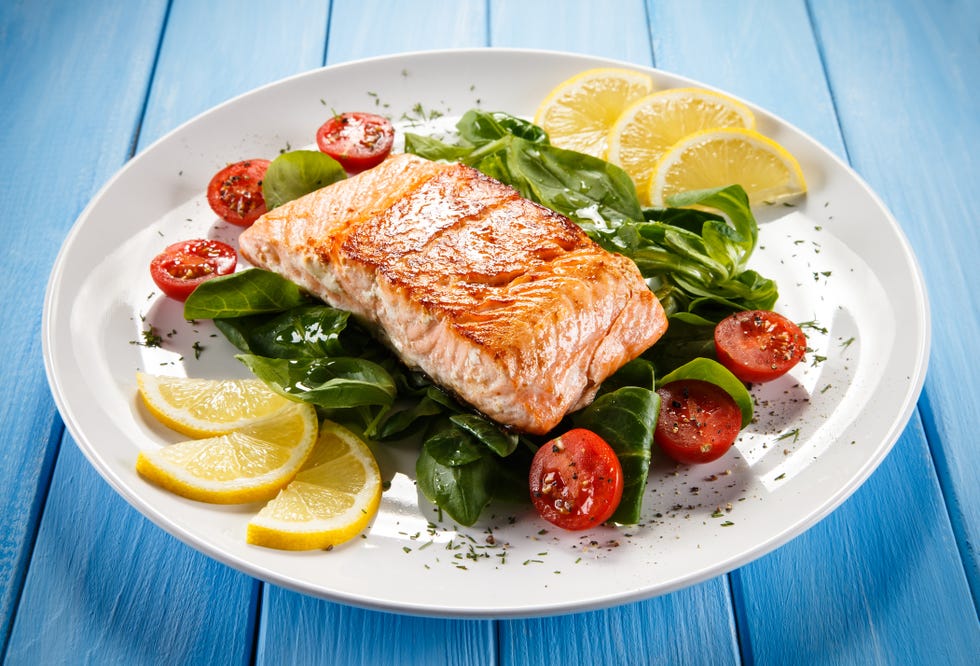 Grilled salmon with French fries and vegetables on wooden table