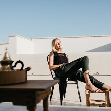 Smiling Young Woman Sitting On Chair At Building Terrace