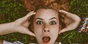 Close-Up Portrait Of Shocked Woman Lying On Field