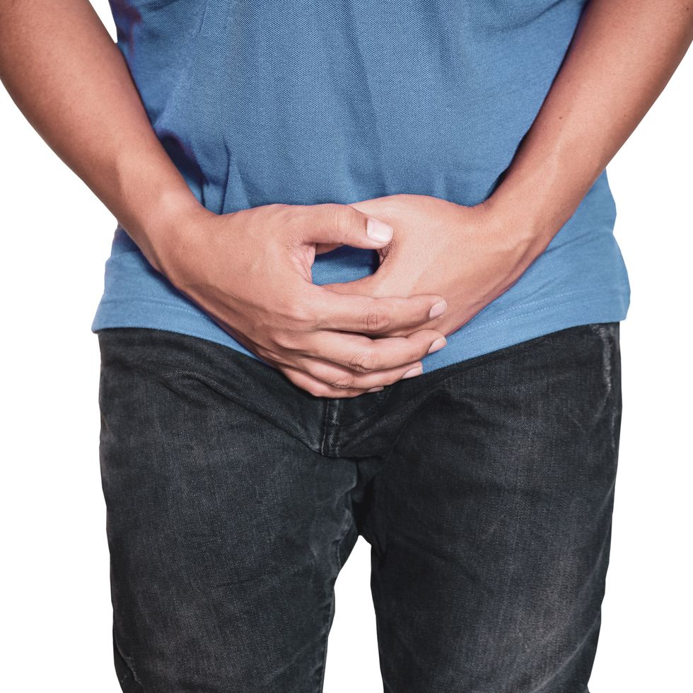 man hands holding on middle crotch of trousers with pain action isolated on white background