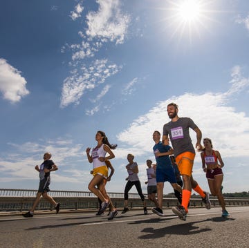 Low angle view of large group of happy athletic people running a marathon race on the road. vista a continuación de atletas felices de distintas edades corriendo un maratón