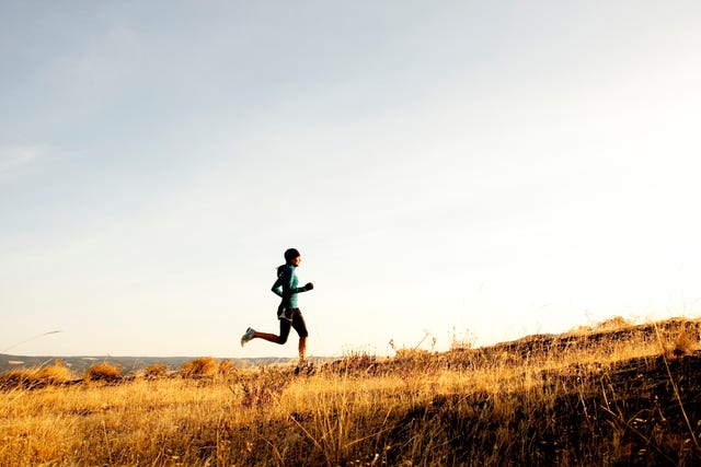 an athletic woman jogging along the columbia river gorge at sunrise